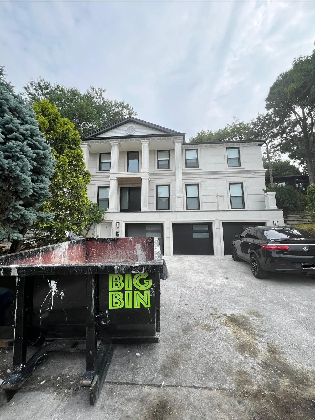 A Big Bin roll-off bin on the driveway of a large custom-built home