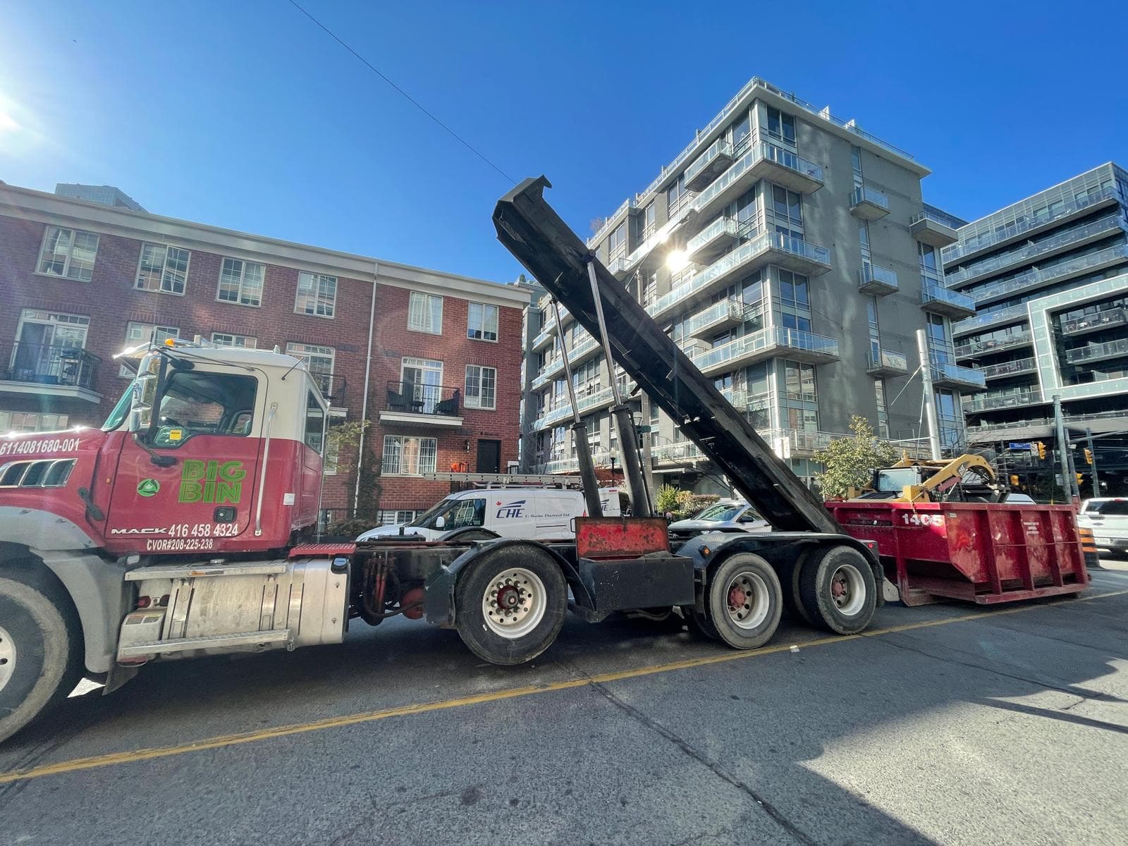 A Big Bin roll-off bin at the curb on a downtown Toronto street lined with condominiums